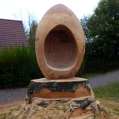 sculpture sur bois d'un siege en forme d'oeuf dans un tronc d'arbre